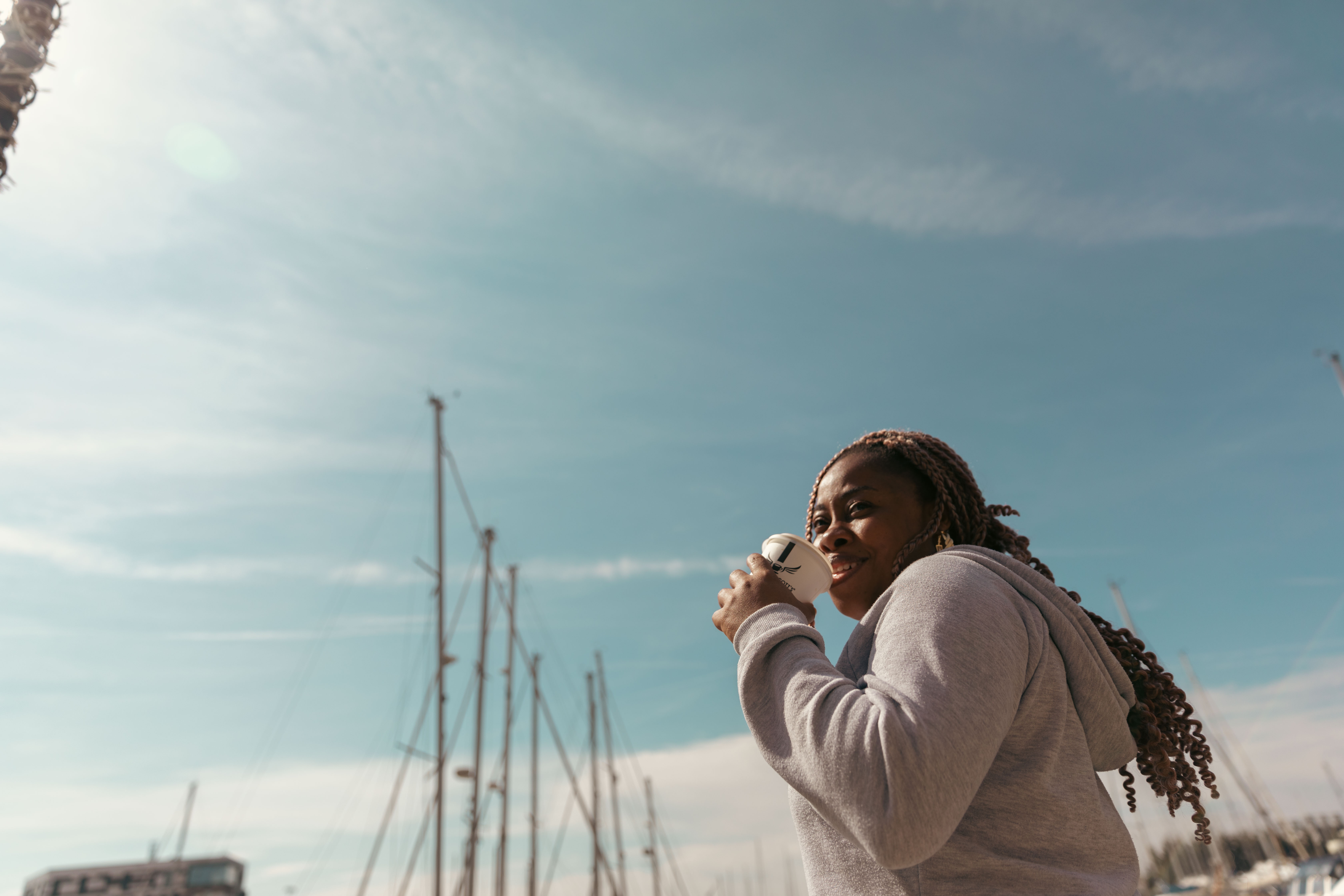 Student with coffee with Ipswich Waterfront in the background